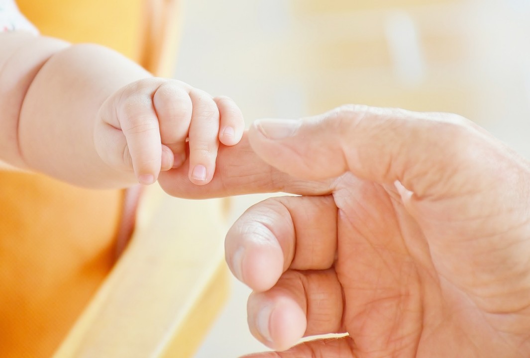A single father touching his baby's hand